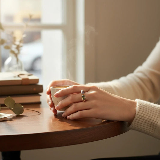 Anillo abierto Ámbar Joyas de plata con dos circonitas en forma de gota, una morada y otra oliva, puesto en una mano