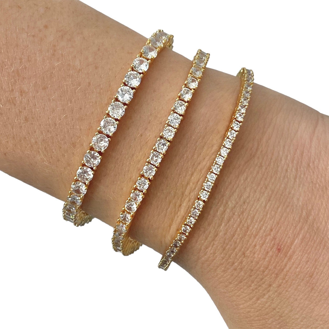 Tres pulseras tennis doradas de distinto grosor en la muñeca