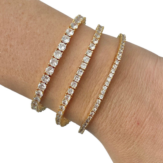 Tres pulseras tennis doradas de distinto grosor en la muñeca