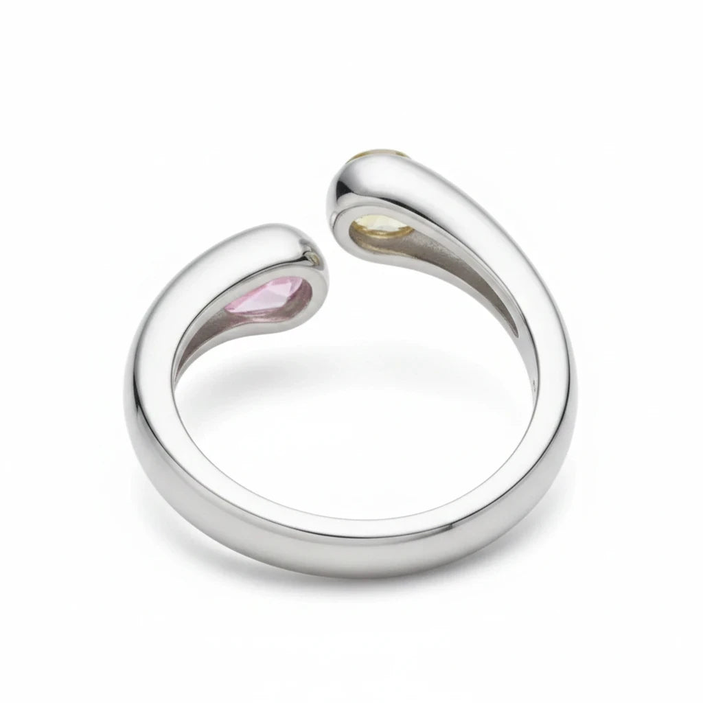 Anillo abierto Ámbar Joyas de plata con dos circonitas en forma de gota, una rosa y otra amarilla, sobre fondo blanco.