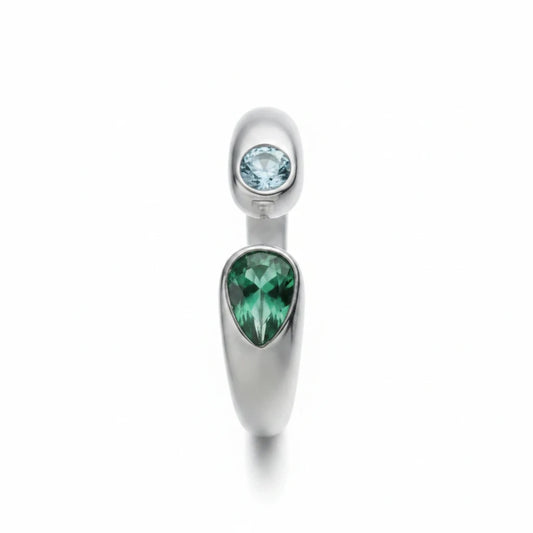 Anillo abierto Ámbar Joyas en tono plateado con dos circonitas en forma de gota, una verde y una azul claro.