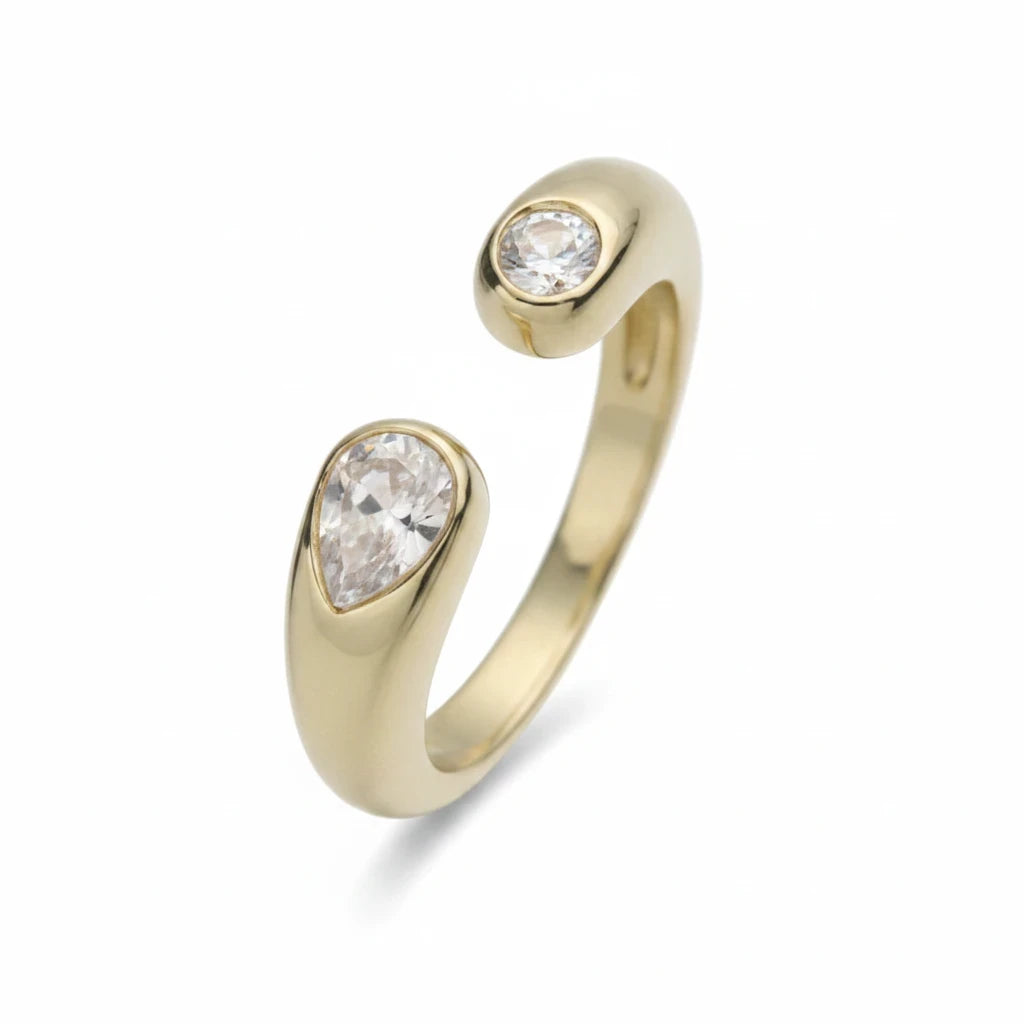 Anillo abierto Ámbar Joyas en tono dorado con dos circonitas blancas en forma de gota, diseño minimalista ajustable.