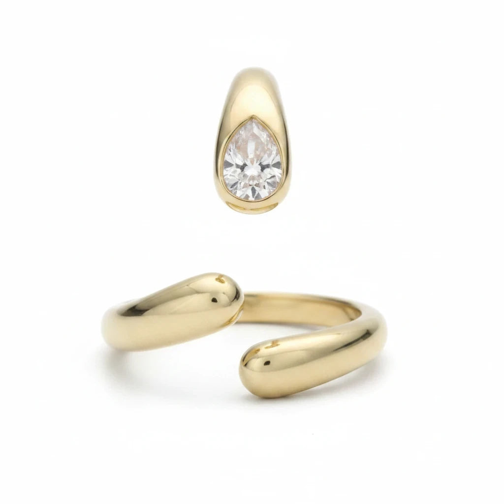 Anillo abierto Ámbar Joyas en tono dorado con dos circonitas blancas en forma de gota, diseño minimalista y ajustable.