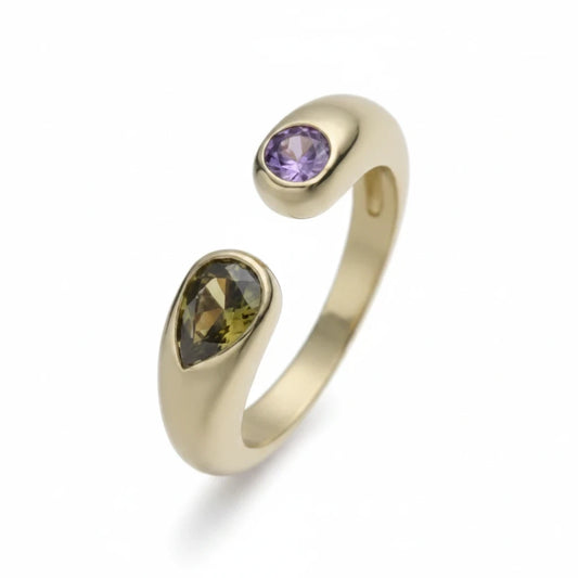 Anillo abierto Ámbar Joyas en tono dorado con piedra gota verde y piedra circular violeta, diseño minimalista moderno.