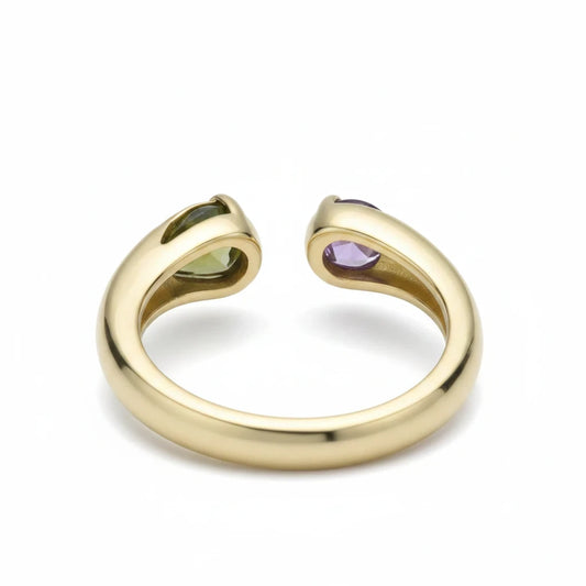 Anillo abierto Ámbar Joyas en tono dorado con una piedra verde en forma de gota y una piedra circular violeta.