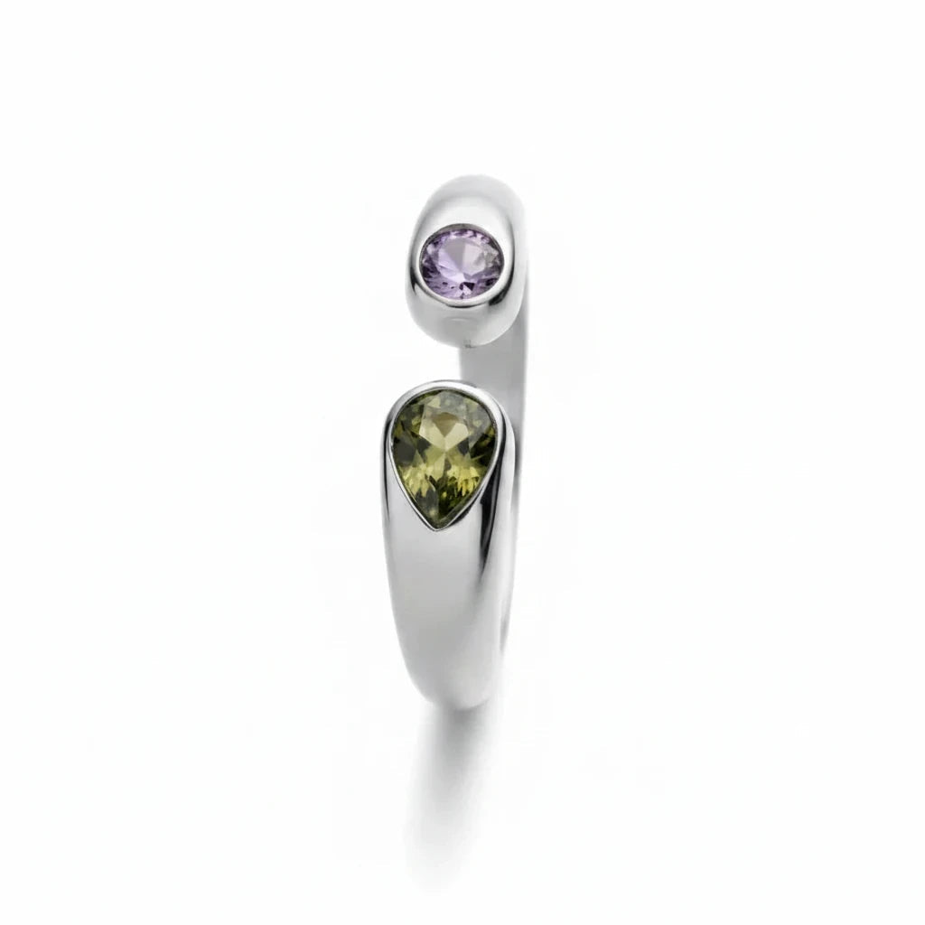 Anillo abierto Ámbar Joyas de plata con dos circonitas en forma de gota, una morada y otra oliva, sobre fondo blanco.