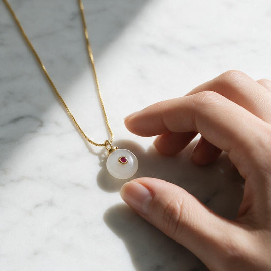 Collar Donut Piedra Luna con Circón Rojo – Baño de Oro, sobre mármol