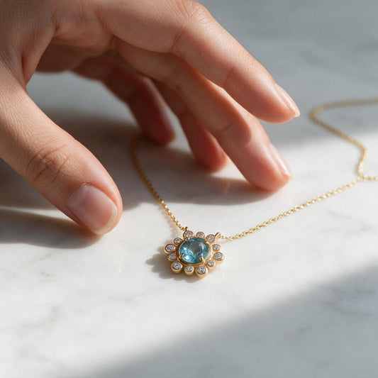 Collar Sol Topacio Azul y Circones – Baño de Oro, sobre mármol